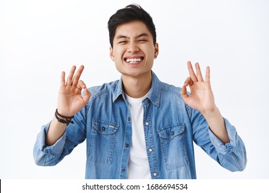 Close-up Portrait Of Charismatic, Attractive Asian Man Guarantee Best Quality, Recommend Product, Laughing And Smiling Pleased, Being Assertive You Will Like It, White Background