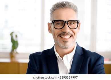 Close-up portrait of cheerful and serene mature modern businessman in smart casual wear, stylish glasses, headshot of senior 60s gray-haired male manager, leader looking at camera with toothy smile - Shutterstock ID 2395539997