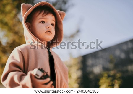 Close-up portrait of child boy in hooded bear plush jumpsuit. Baby playing outside