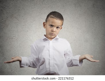 Closeup portrait clueless, unhappy child boy with arms out asking what's problem who cares, so what, I don't know isolated grey wall background. Negative human emotion facial expression body language 