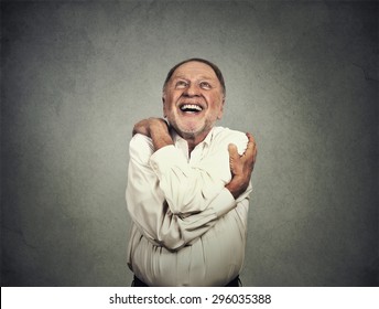 Closeup Portrait Confident Smiling Man Holding Hugging Himself Isolated On Grey Wall Background. Positive Human Emotion, Facial Expression, Feeling, Reaction, Attitude. Love Yourself Concept