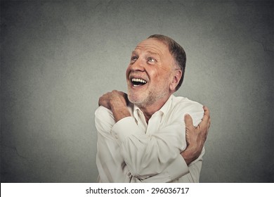 Closeup Portrait Confident Smiling Man Holding Hugging Himself Isolated On Grey Wall Background. Positive Human Emotion, Facial Expression, Feeling, Reaction, Attitude. Love Yourself Concept