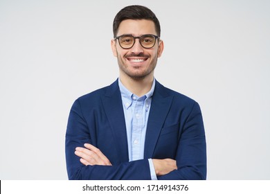 Close-up Portrait Of Confident Young Businessman Wearing Blue Blazer And Smart Casual Shirt, Smiling At Camera, Holding Arms Crossed, Standing Isolated On Gray Background