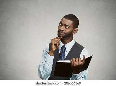 Closeup Portrait Confused, Unhappy Serious Man Holding, Reading  Book, Having Many Questions, Thinking, Isolated Black Background. Human Face Expressions, Emotions, Perception, Body Language, Reaction