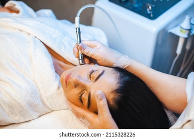 Close-up portrait of cosmetologist's hands making microdermabrasion procedure on the face of a woman in a beauty salon. Facial skin treatment. Cosmetology
