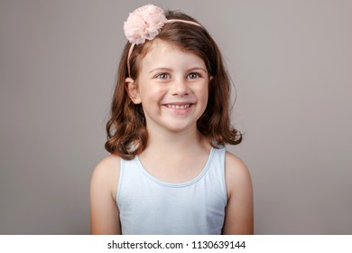 Closeup Portrait Of Cute Adorable White Brunette Caucasian Preschool Girl Making Faces In Front Of Camera. Child Smiling Laughing Posing In Studio On Plain Light Background. Kid Expressing Emotions