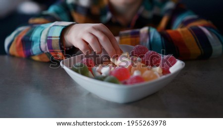 Close-up portrait of cute child boy eating a tasty candie closing eyes in satifaction enjoying leisure activity. Sugar addiction concept.
