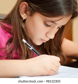 Close-up Portrait Of A Cute Hispanic Girl Writing On Her School Notebook