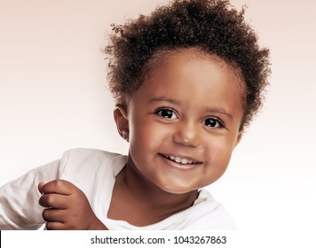 Closeup portrait of a cute little african american boy isolated on beige white background, sweet kid having fun in the studio, happiness and carefree childhood concept