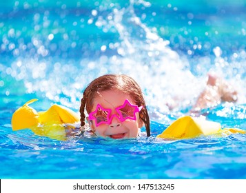 Closeup portrait of cute little arabic girl swimming in the pool, happy child having fun in water, beach resort, summer vacation and holidays concept