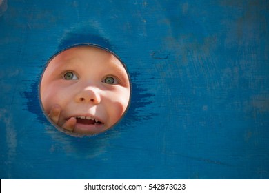 Closeup Portrait Of Cute Little Toddler Boy Looking Into Blue Wooden Frame At Playground. Curiosity, Exploration And Leaning. Activities For Children Outdoors. Preschool Daycare. Small Boy Playing