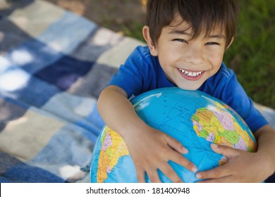 Close-up portrait of a cute young boy holding globe at the park - Powered by Shutterstock