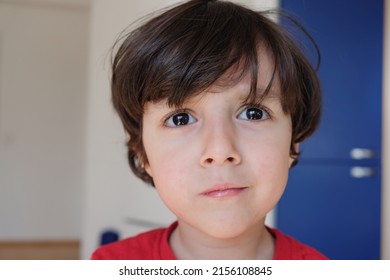 Closeup Portrait Of Cute Young Kid With Eyes Wide Open And His Bangs Over His Forehead. He Is Looking Puzzled