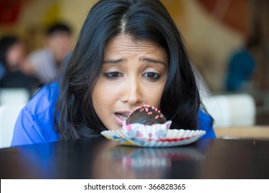 Closeup portrait of desperate woman in blue shirt craving fudge with pink sprinkles dessert, eager to eat, isolated indoors background