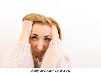 Close-up portrait of disappointed discouraged woman with blond hair and soft pink sweater. Girl is isolated on white background. Copy space for design