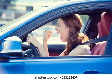 Closeup portrait displeased angry pissed off aggressive woman driving car shouting at someone hand fist up in air isolated traffic background. Emotional intelligence concept. Negative human expression