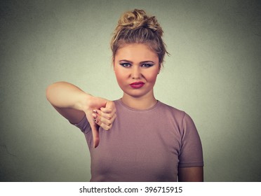 Closeup portrait displeased angry pissed off woman annoyed giving thumbs down gesture looking with negative facial expression, disapproval, isolated on gray background. Human emotions attitude