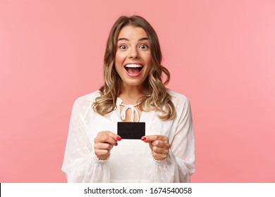 Close-up portrait of excited and happy good-looking blond female recommend bank, smiling amazed, holding credit card, paying for purchase, shopaholic in store feel upbeat