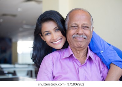 Closeup portrait, family, young woman in blue shirt holding older man in pink collar button down from behind, happy isolated indoors home background