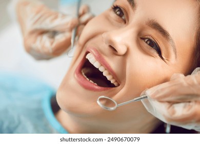 Close-up portrait of female patient with open mouth in modern dentistry clinic during medical check up in medical center. Dentist examining young woman teeth with dental tools. Dental health care. - Powered by Shutterstock