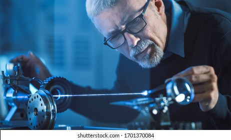Close-up Portrait of Focused Middle Aged Engineer in Glasses Working with High Precision Laser Equipment, Using Lenses and Testing Optics for Accuracy Required Electronics