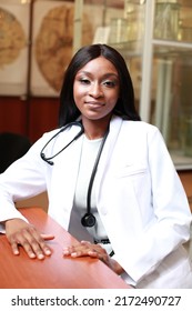 Closeup Portrait Of Friendly, Smiling Confident Black Nigerian Female Doctor, Healthcare Professional In Scrubs With Stethoscope, Sitting In Scientific Research Room Laboratory. Student Intern.
