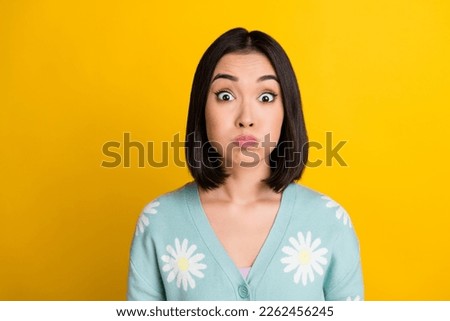 Closeup portrait of funky childish goofy japanese girl black bob hairstyle pouted cheeks playful hold breath isolated on yellow color background