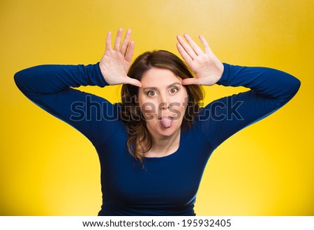 Closeup portrait funny, foolish, young, childish rude bully woman sticking tongue out at you camera gesture, isolated yellow background. Human emotions, facial expressions, feelings. Signs, symbols