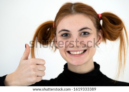 Closeup portrait of a funny redhead teenage girl with childish hairstyle smiling happily isolated on white backround.