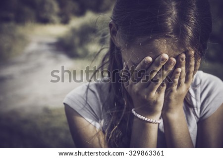 close-up portrait of a girl crying and covering her face