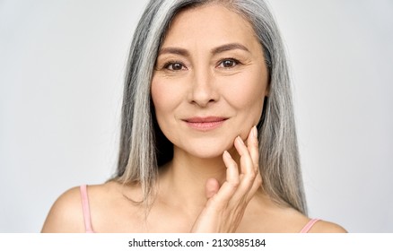 Closeup portrait of gorgeous happy middle aged mature asian woman, senior older 50 year lady looking at camera touching her face isolated on white. Ads of lifting anti wrinkle skin care treatment. - Shutterstock ID 2130385184