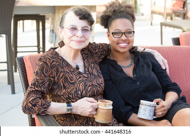 Closeup portrait, granddaughter and grandmother sitting, enjoying drinks coffee and tea together, isolated outdoors background