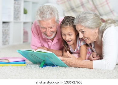 Close-up portrait of grandparents reading book with little granddaughter