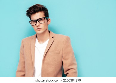 Closeup Portrait Of Handsome Confident Stylish Hipster Lambersexual Model. Sexy Modern Man Dressed In Elegant Beige Suit. Fashion Male Posing In Studio Near Blue Wall. In Spectacles