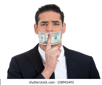 Closeup portrait of handsome corrupt guy in black suit with twenty dollar bill taped to mouth and showing shhh sign, isolated on white background. Bribery concept in politics, business, and diplomacy.