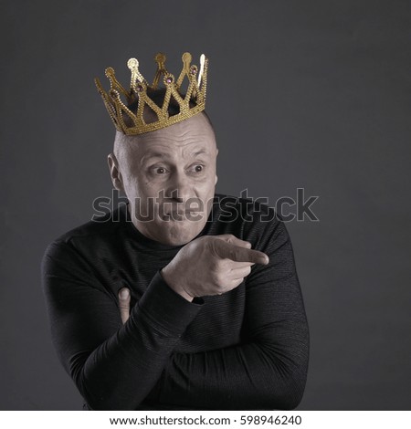 closeup portrait handsome man in a black shirt and a crown on a gray background studio