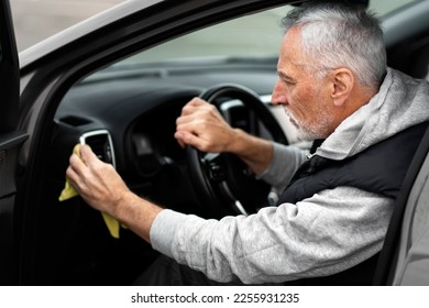 Close-up portrait of handsome positive gray-bearded man driver, waxing and polishing the inside of his car with a yellow microfiber cloth. Detailing and valeting concept. Car maintenance - Powered by Shutterstock