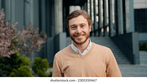 Close-up portrait of handsome success man, looking up at camera, smiling at office building background. Outdoors - Powered by Shutterstock