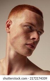 Close-up Portrait Of Handsome Young Red-haired Man With Freckles Posing Isolated Over Grey Studio Background. Expressed Cheekbone Line. Male Beauty. Concept Of Men's Health, Posing, Body And Skin Care