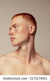 Close-up portrait of handsome young red-haired man posing isolated over grey studio background. Male natural beauty. Concept of men's health, posing, beauty, body and skin care. Model with freckles