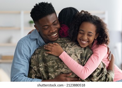 Closeup portrait of happy african american family father and daughter greeting mother soldier at home, emotional black teen girl and man hugging with closed eyes woman in camouflage uniform - Powered by Shutterstock