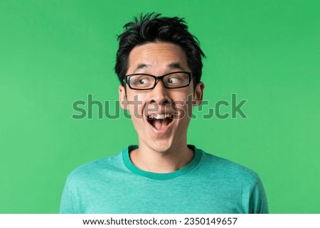 Closeup portrait of a happy AsianChinese man looking sideways. Against green background.