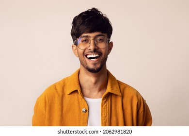 Closeup portrait of happy bearded arabic guy wearing glasses laughing at camera over grey studio background, copy space. Handsome middle-eastern young man in casual showing positive emotions