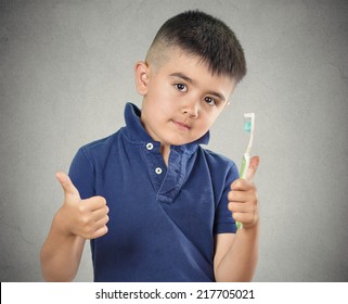 Closeup portrait happy boy brushing his teeth with toothpaste manual toothbrush showing thumbs up isolated grey wall background. Oral dental health, hygiene disease prevention. Face expressions.  - Powered by Shutterstock