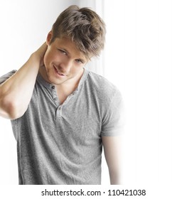 Closeup Portrait Of A Happy Handsome Young Guy With Playful Smirk Near Big Window