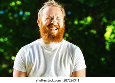 Closeup Portrait Of Happy Mature Man With Red Beard And Mustache Is Laughing At Summer Green Park Background.