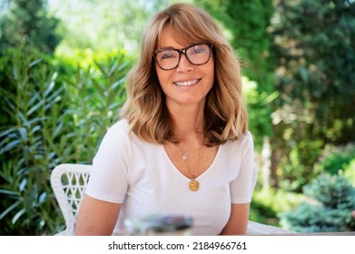 Close-up Portrait Of Happy Middle Aged Woman Sitting In A Lounge Chair While Relaxing At The Backyard.