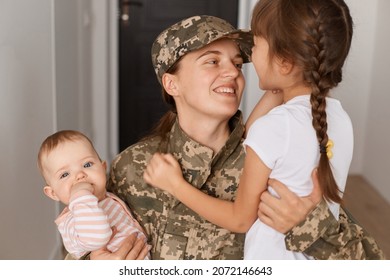 Closeup portrait of happy military mother wearing camouflage uniform and hat, hugging her daughters while returning home after served in army, expressing happiness. - Powered by Shutterstock