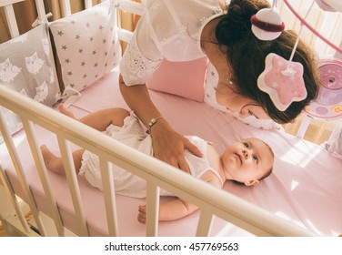 Close-up Portrait Of A Happy Mother Laughing With Cute Baby In Crib