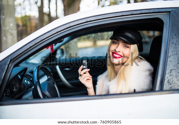Closeup portrait happy, smiling, attractive\
woman, buyer sitting in her new white car showing keys isolated\
outdoors street dealership lot background. Personal transportation,\
auto purchase concept